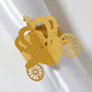 Close-up of golden laser-cut carriage napkin ring on white satin fabric