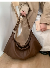 Close-up of deep brown tote bag with pleated texture and silver ring shoulder strap