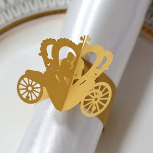Detail of gold laser-cut crown carriage napkin ring on silk napkin for wedding decor