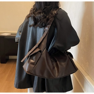 Détail du sac cabas en cuir souple marron avec large bandoulière et œillets argentés