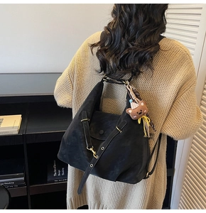 Close-up of black matte texture backpack with cute bear pendant and metal eyelet strap