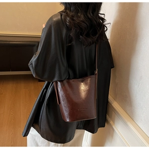 Brown leather bucket bag with fashion embossing shown in a stylish crossbody look