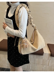 Detail of ruched shoulder strap and cute bear pendant on beige oversized tote bag