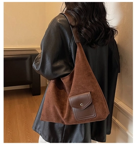 Borsa tote in camoscio marrone con tasca in pelle indossata a spalla in un interno