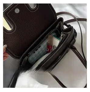 Top view of dark brown pebbled leather bag interior with zipper compartment and accessories