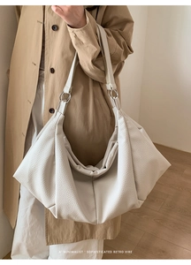 Detailed view of white lychee leather tote bag with silver ring hardware on khaki trench