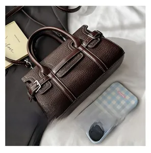Detailed view of deep brown leather Boston bag with white stitching and leather texture