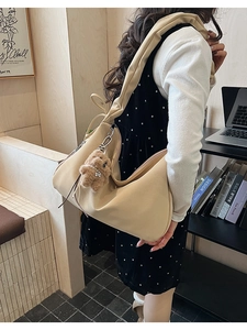 Detail of beige textured leather tote bag with a cute brown plush bear charm accessory