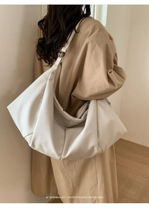 Close-up of white oversized pleated tote bag with silver hardware and soft pebble texture