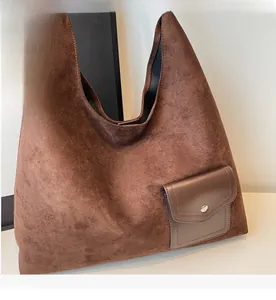 Detail of dark brown faux suede hobo tote bag featuring a front pocket and silver buckle