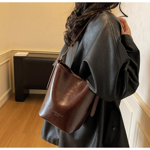 Detail of vintage dark brown bucket bag showing polished leather texture and crossbody strap