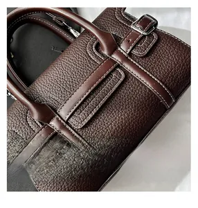 Detail of dark brown pebble leather handbag with silver buckle and contrast stitching