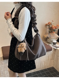 Detail of dark brown tote bag featuring cloud pleated strap and cute plush bear charm