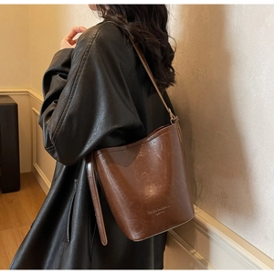 Brown vintage bucket bag detail showing side buckle and shoulder strap fit on model