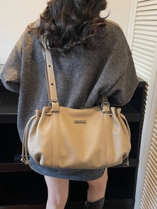Sac fourre-tout minimaliste en cuir beige avec cordons, porté à l'épaule sur mannequin