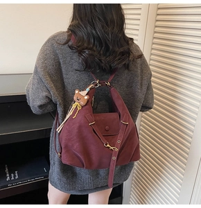 Detail view of burgundy leather tote bag with brown bear charm and adjustable straps