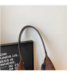 Close-up of the durable brown suede tote bag handles with reinforced edge stitching