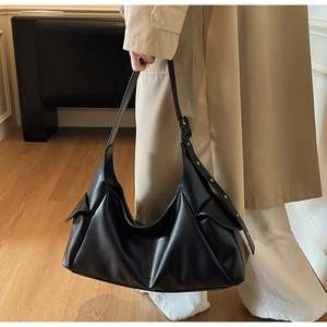 Détail latéral du sac cabas noir montrant les rivets argentés et la poche à rabat