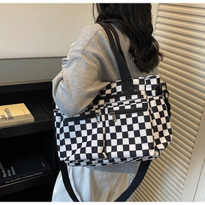 Detail view of checkered corduroy tote bag with dual front zipper pockets and shoulder strap