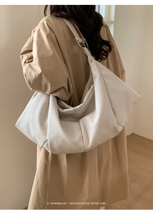 Detail of white pleated tote bag showing premium pebble grain texture and silver metal rings