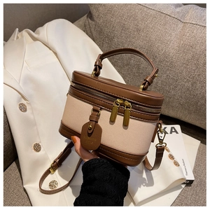 Dettaglio borsa cilindrica retrò in tela beige con rifiniture in pelle marrone e tracolla