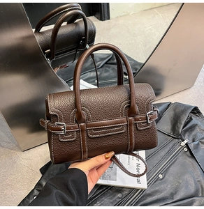 Detail der dunkelbraunen Handtasche aus genarbtem Leder mit Kontrastnähten und Griffen
