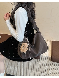 Detail of dark brown tote bag with ruffled strap and plush teddy bear charm accessory