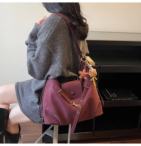 Detail view of burgundy leather tote with star bear charm on a dark library background