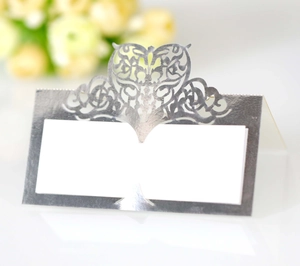 Macro detail of laser cut silver place card with heart vine pattern for weddings
