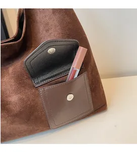 Detailed shot of dark brown suede tote bag with leather front pocket and silver magnetic clasp