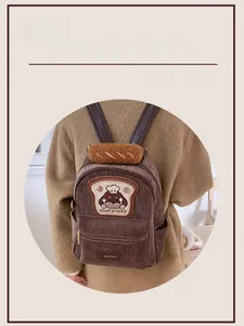 Close-up of brown corduroy backpack with cute chef puppy patch and croissant detail