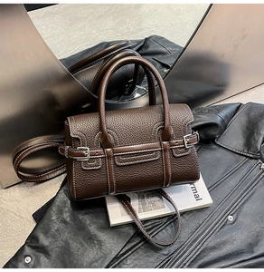 Detail der dunkelbraunen Bowling-Tasche aus Leder mit Narbung auf einer schwarzen Lederjacke