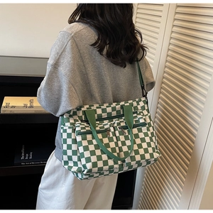 Detail view of large green and white checkerboard canvas tote bag with dual front zipper pockets