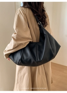 Close-up of black retro hobo bag with pleated leather texture and silver metal rings