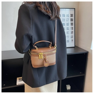 Mini borsa a scatola retrò marrone e beige indossata a tracolla da una modella
