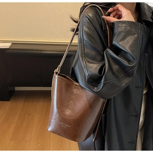 Detail of vintage brown leather bucket bag with fashion engraving worn by a model