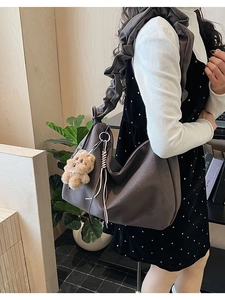 Detail of grey tote bag with pleated ruffled strap and brown plush bear charm