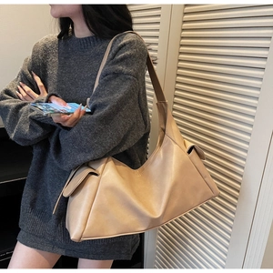 Détail du sac hobo en similicuir abricot avec de grandes poches latérales et texture lisse