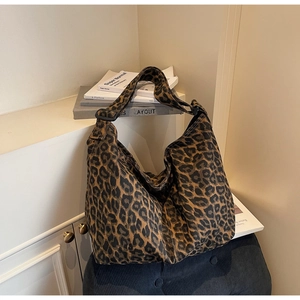 Close-up of leopard print canvas tote bag with adjustable black strap on a chair