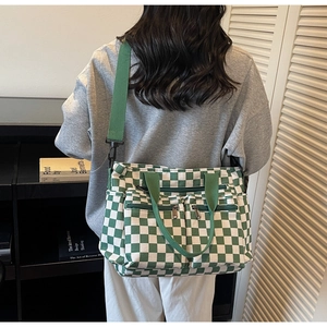 Detail of green checkerboard canvas tote with dual zipper pockets and adjustable strap