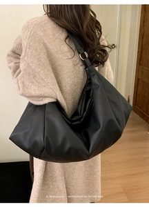 Detail of black pleated leather tote bag with silver ring on the shoulder strap