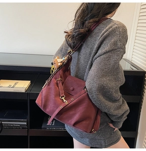 Detail of burgundy vintage tote bag with bear charm and striped scarf on model