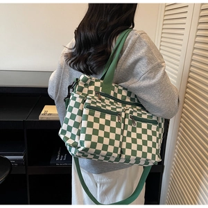Close-up of green and white checkered canvas bag with double front zip pockets and shoulder strap