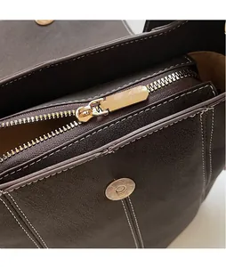 Detailaufnahme der dunkelbraunen Ledertasche mit goldenem Reißverschluss und Kontrastnaht