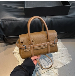 Detail der karamellbraunen Lederhandtasche mit weißen Nähten und Metallschnalle