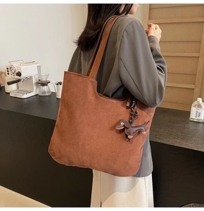 Détail du grand sac cabas en suédine marron avec un pendentif décoratif en forme de teckel