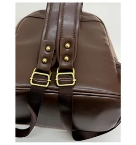 Detail of vintage gold metal buckle and dark brown leather texture on a stylish backpack