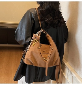 Vintage brown leather tote bag detail with cute teddy bear charm and adjustable strap