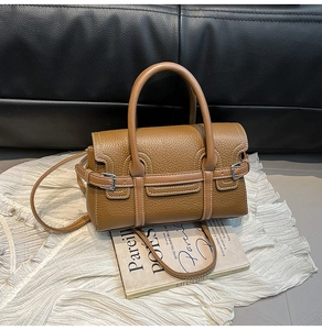 Detailansicht der braunen Ledertasche mit Lychee-Narbung, Kontrastnähten und Metallschnalle