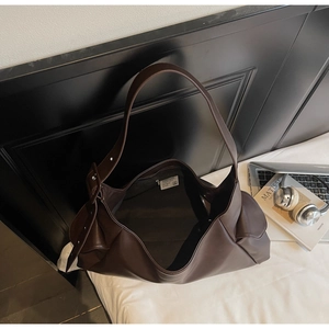 Vue de dessus d'un grand cabas marron foncé avec bandoulière large et accessoires